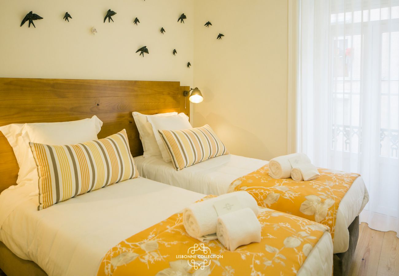2 camas de solteiro com xadrez amarelo e andorinhas na parede